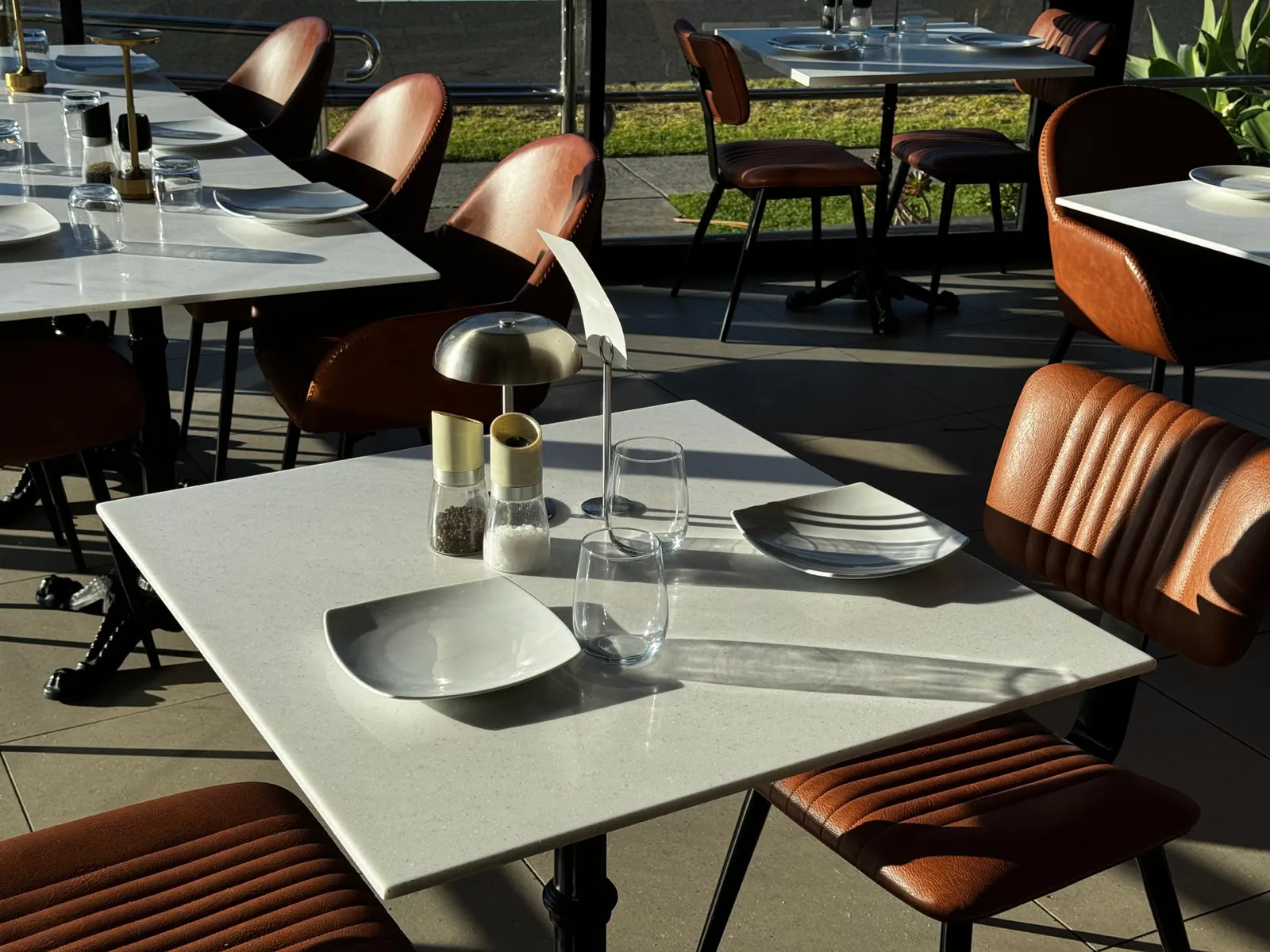 Marble tables and tan leather chairs set for service by the windows